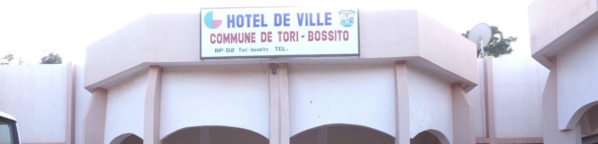 Bâtiment avec un panneau indiquant Hôtel de Ville Commune de Tori-Bossito sous un ciel clair