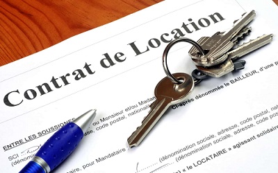 Clés posées sur un contrat de location accompagné d un stylo bleu sur une surface en bois