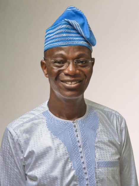 Homme souriant portant une tenue traditionnelle blanche et un bonnet bleu orné de motifs blancs