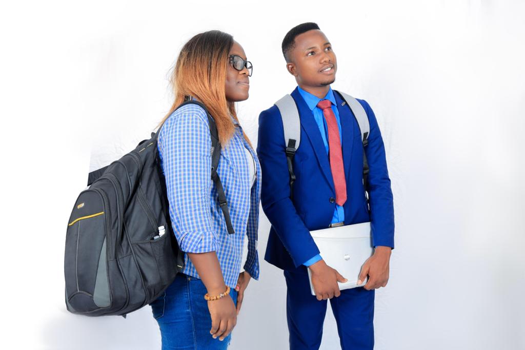 Deux étudiants debout avec sacs à dos, l’un en chemise à carreaux et l’autre en costume bleu avec cravate rouge, regardant à droite