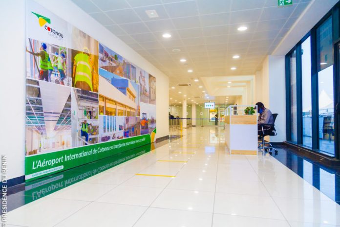 Couloir vide d’un hall d’aéroport avec un comptoir d’accueil et une grande bannière illustrée sur le mur à gauche