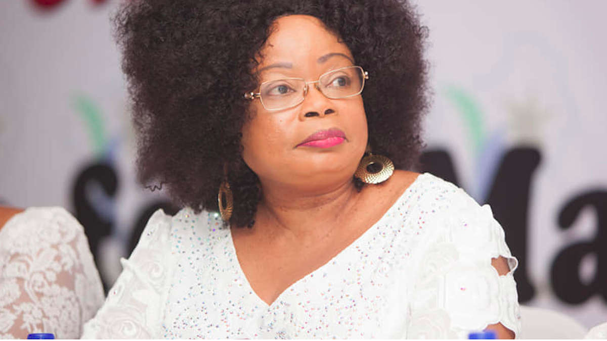 Femme portant une blouse blanche à motifs dentelle et coiffure afro regardant vers la droite avec un fond flou