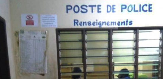 Guichet fermé d’un poste de police avec deux personnes visibles à l’intérieur derrière une grille.