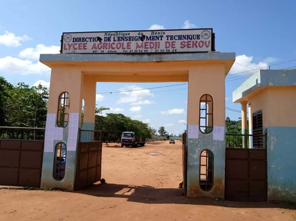 Entrée principale d un lycée agricole avec un portail ouvert et un véhicule stationné en arrière-plan sous un ciel bleu