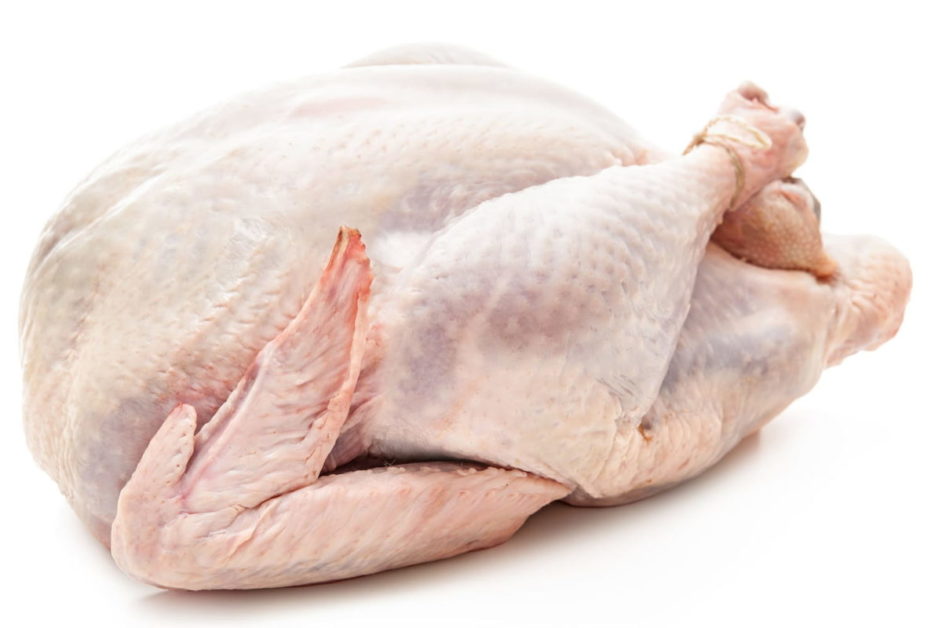 Dinde entière crue prête à la cuisson avec pattes attachées sur fond blanc