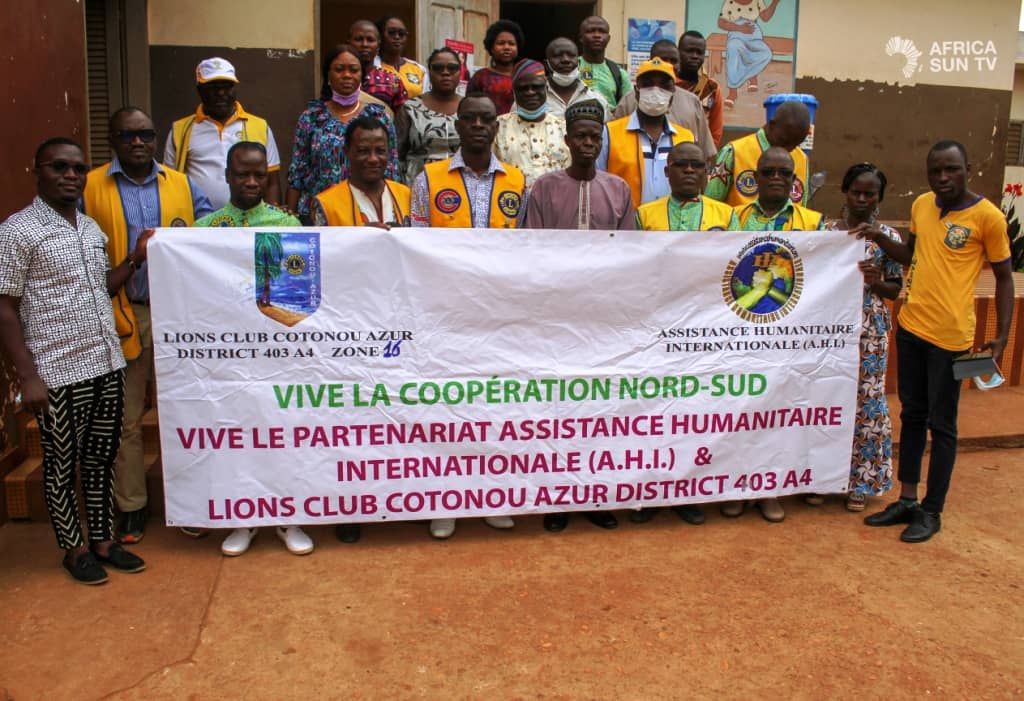 Un groupe de personnes posant derrière une banderole célébrant un partenariat humanitaire entre deux organisations