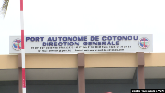 Enseigne du Port Autonome de Cotonou avec les contacts téléphoniques et le site web visibles sur un bâtiment beige