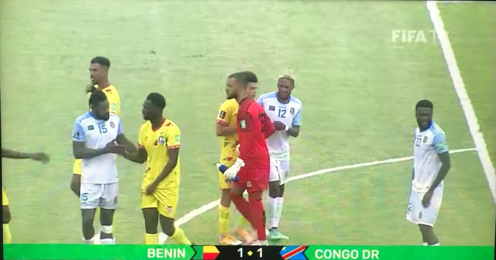 Des joueurs de deux équipes de football discutent et se serrent la main au milieu du terrain pendant un match à égalité 1-1