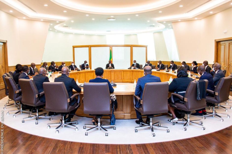 Des personnes en tenue formelle sont réunies autour d'une grande table ronde dans une salle lumineuse.