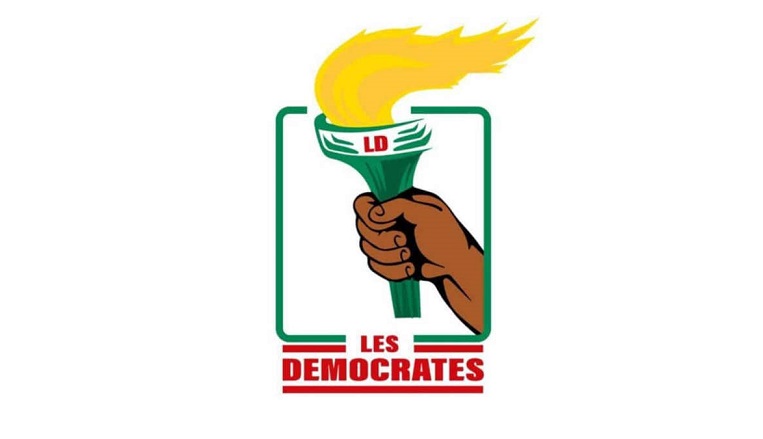 Main tenant un flambeau allumé avec une bannière verte et le texte Les Democrates en dessous