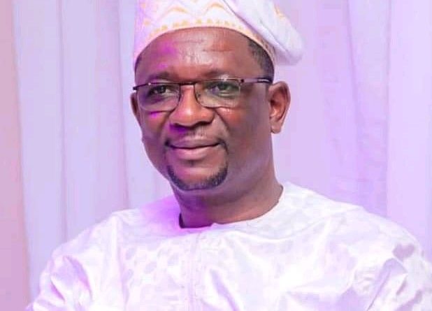 Homme souriant portant une tenue traditionnelle blanche et un bonnet assorti sur un fond blanc.