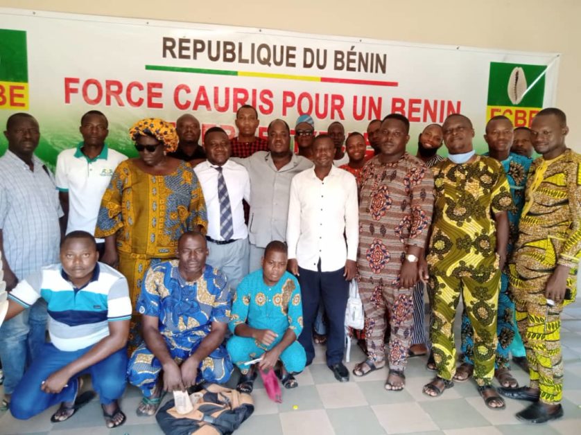 Groupe d'hommes posant devant une banderole avec inscriptions en français sur un mur intérieur