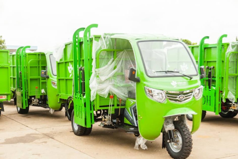Plusieurs tricycles verts de collecte des déchets stationnés sur une surface en béton en extérieur