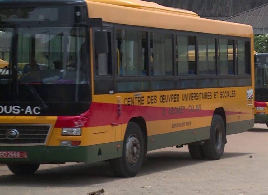 Bus jaune et rouge avec l'inscription centre des œuvres universitaires et scolaires circulant sur une voie urbaine