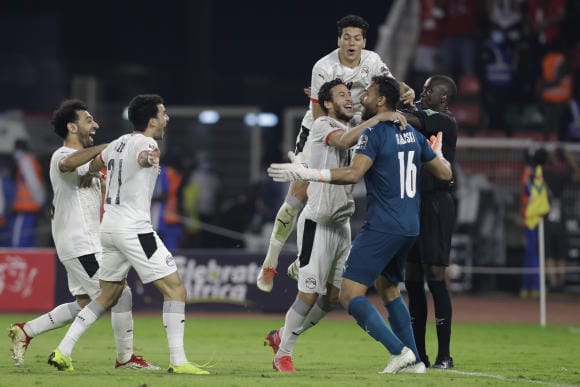 Des joueurs de football en maillots clairs célèbrent un but sur le terrain avec enthousiasme et joie partagée