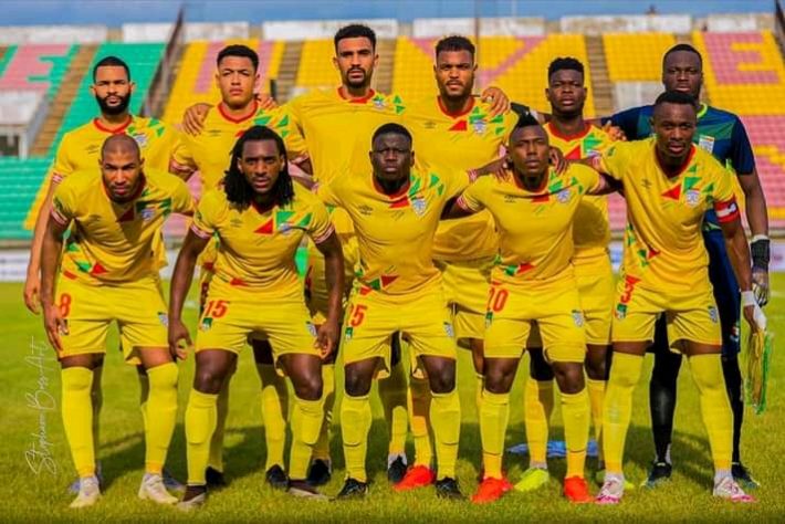 Onze joueurs de football portant un maillot jaune posent ensemble sur un terrain de stade vide