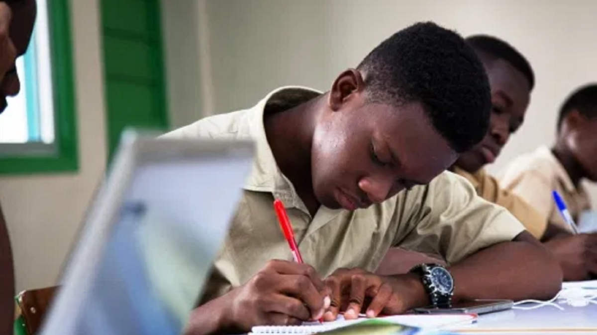 Des élèves concentrés écrivant dans un cahier lors d’un examen en salle de classe