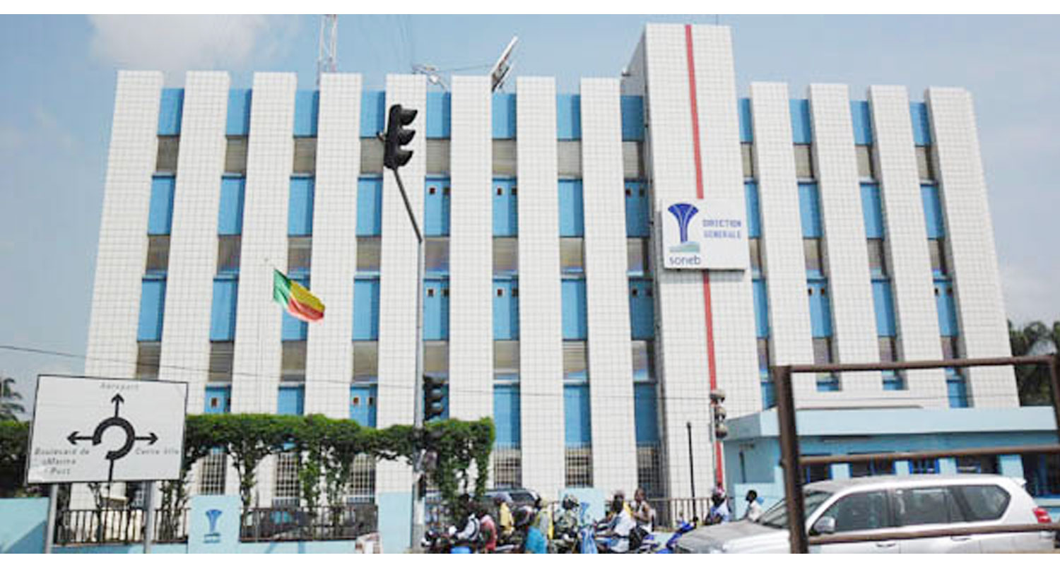 Bâtiment administratif de plusieurs étages avec un drapeau tricolore soutenu par une barrière bleue au premier plan