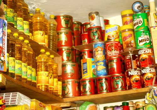 Des étagères remplies de bouteilles d’huile, conserves alimentaires et boîtes de boissons en poudre empilées
