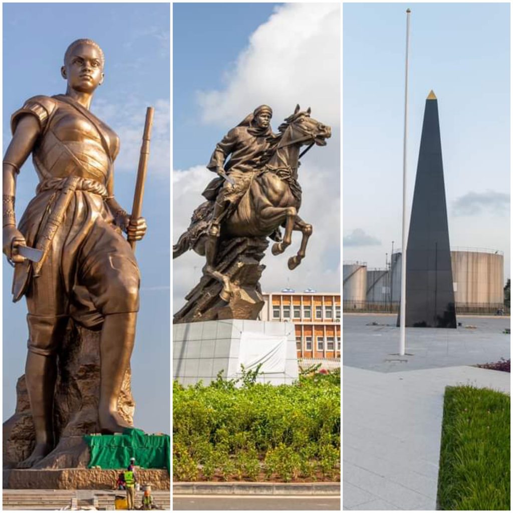 Trois monuments publics en bronze représentant un guerrier, un cavalier et une obélisque sur esplanade urbaine verdoyante