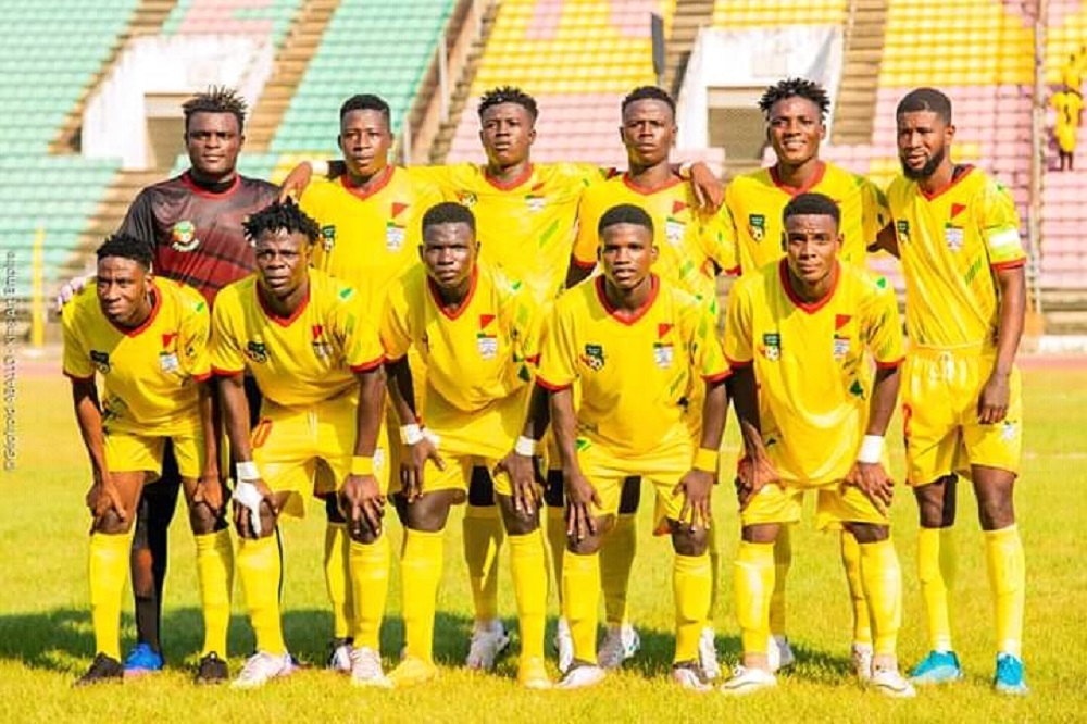 Onze joueurs de football en maillot jaune posent sur un terrain de stade devant des gradins vides