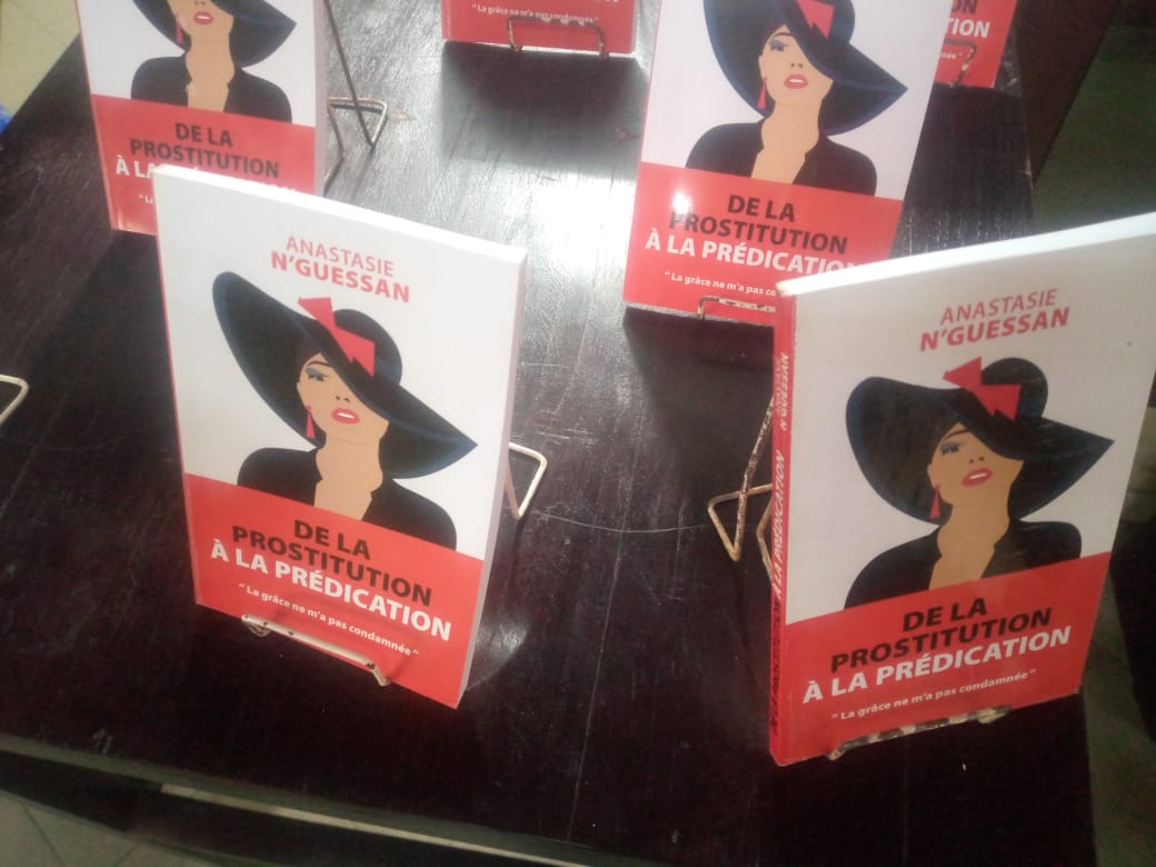 Plusieurs exemplaires d un livre avec une couverture montrant une femme au chapeau noir et titre rouge sur fond blanc posés sur une table noire