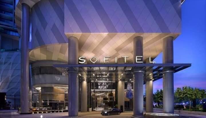 Entrée illuminée d’un grand bâtiment avec le nom SOFITEL en lettres lumineuses au-dessus du porche