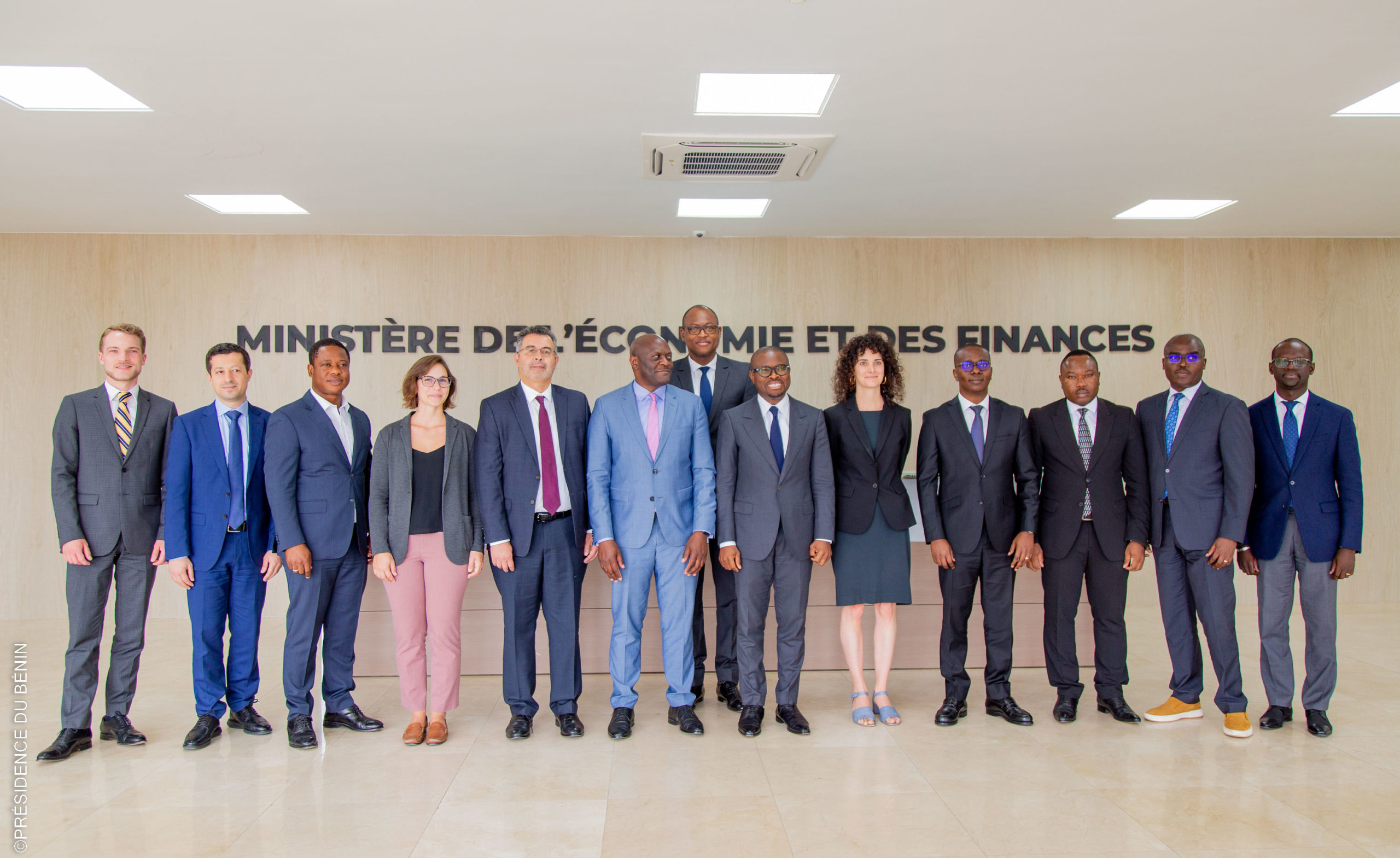 Un groupe de personnes en tenue professionnelle posant devant un mur avec l'inscription ministère de l'économie et des finances