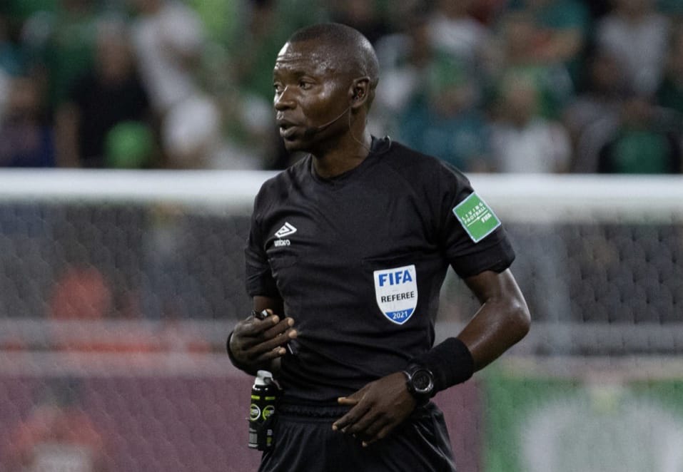 Arbitre en tenue noire avec badge FIFA sur le terrain de football pendant un match