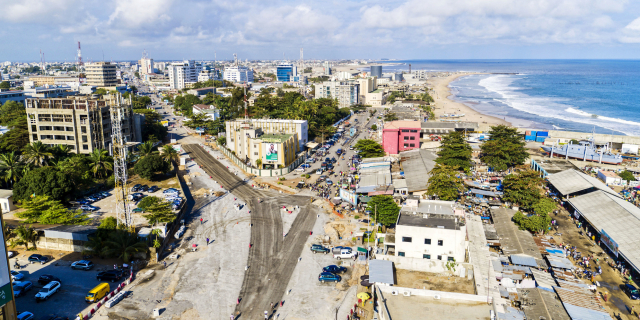 Vue aérienne d’une ville côtière avec bâtiments, route en travaux et plage au bord de l’océan