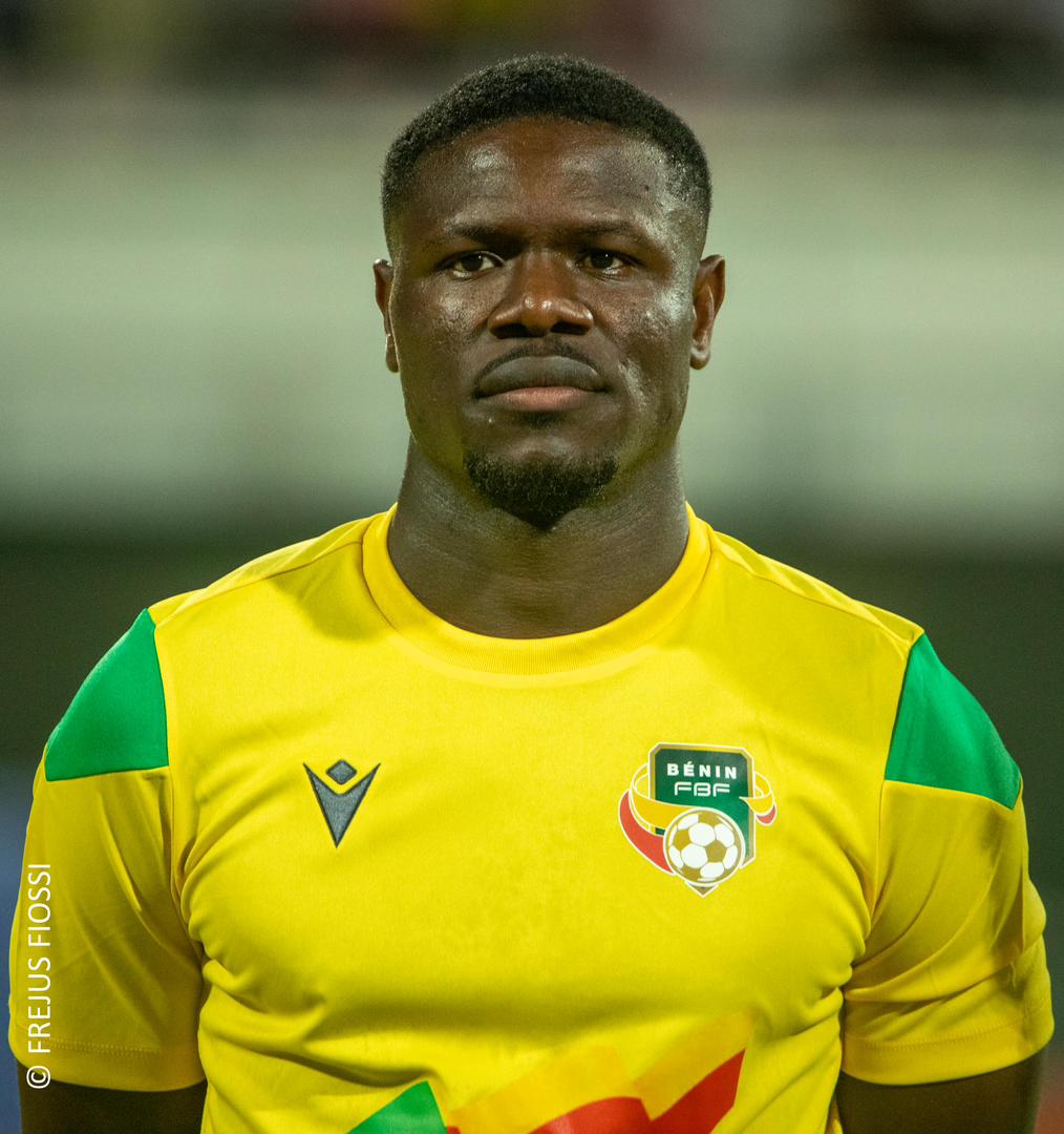 Homme portant un maillot de football jaune orné d’un écusson vert et blanc avec un ballon et le texte «BÉNIN FBF