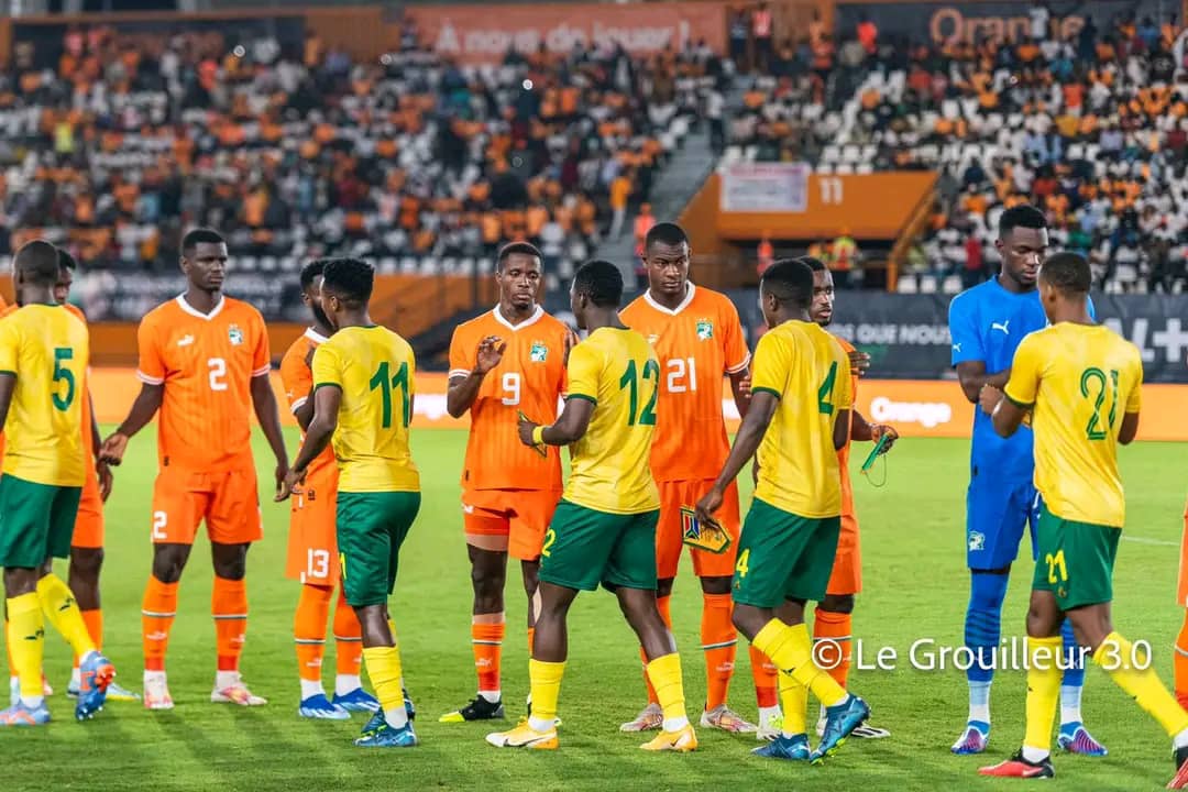 Des joueurs de deux équipes de football se saluent sur le terrain avant le début du match sous les projecteurs du stade