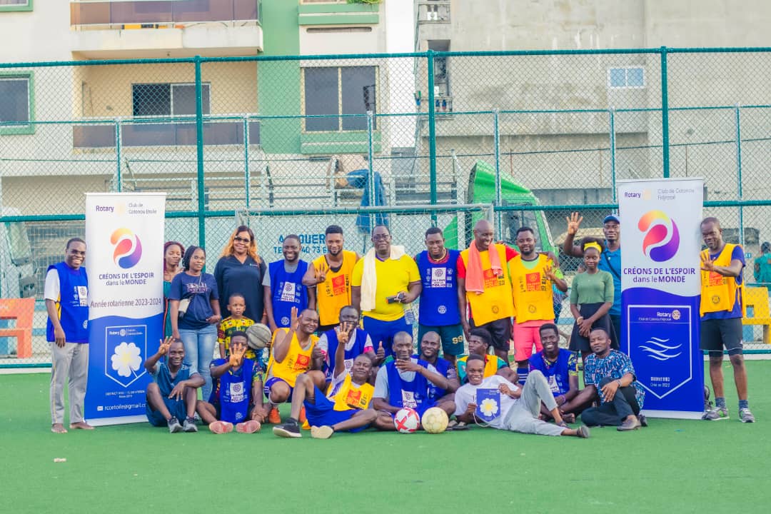 Groupe de personnes posant sur un terrain de football avec deux banderoles Rotary de chaque côté