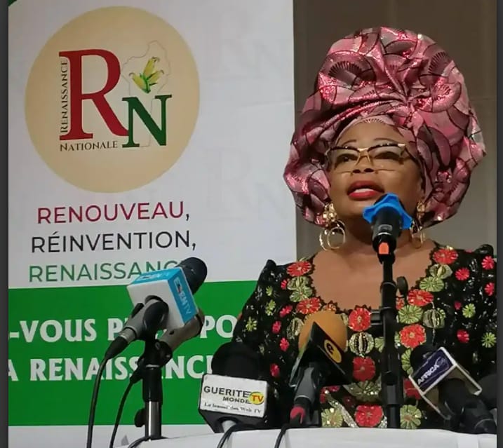Femme en tenue traditionnelle colorée parlant au micro devant un panneau avec les mots Renouveau et Renaissance