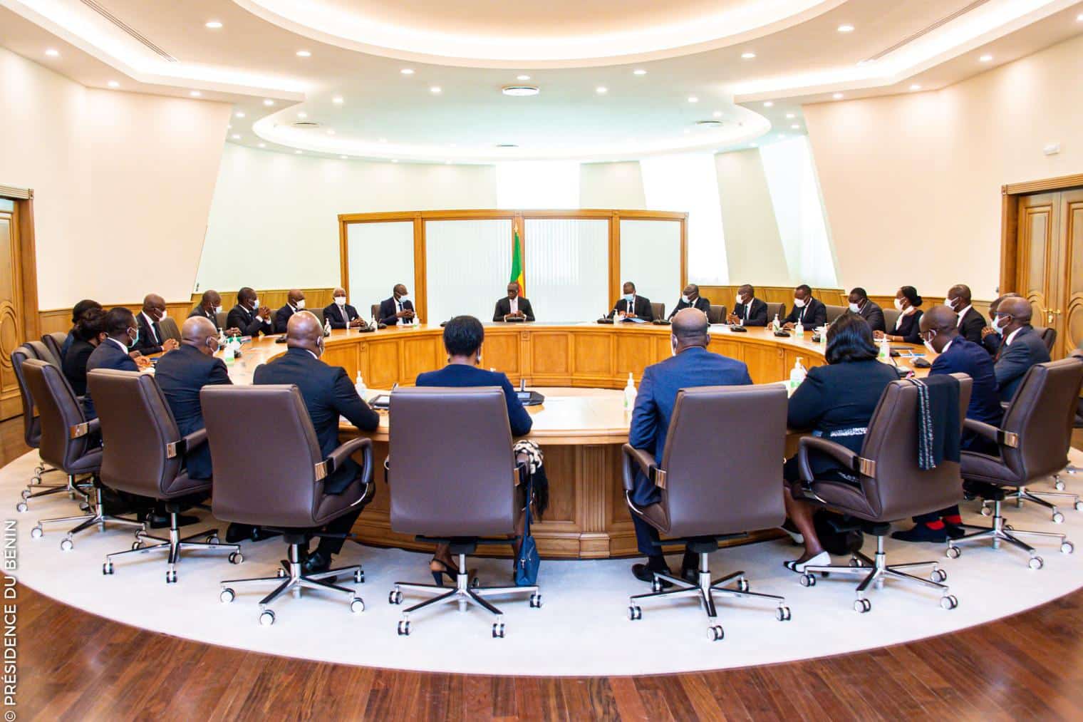 Personnes en réunion autour d'une grande table ronde dans une salle lumineuse avec sièges en cuir marron