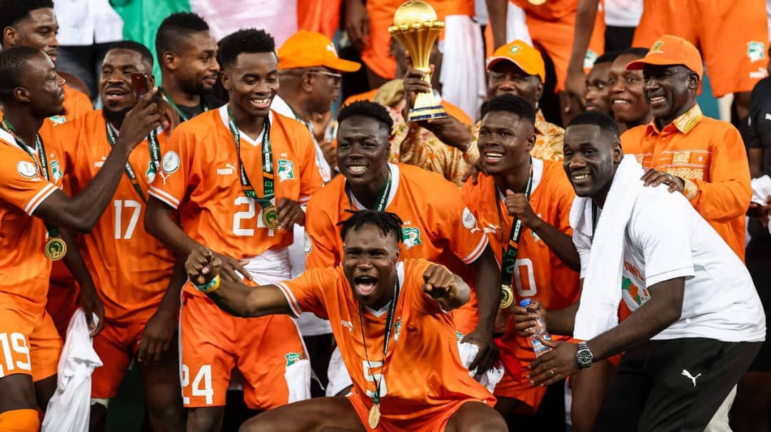 Joueurs en maillots orange célébrant ensemble avec un trophée doré lors d’un événement sportif important