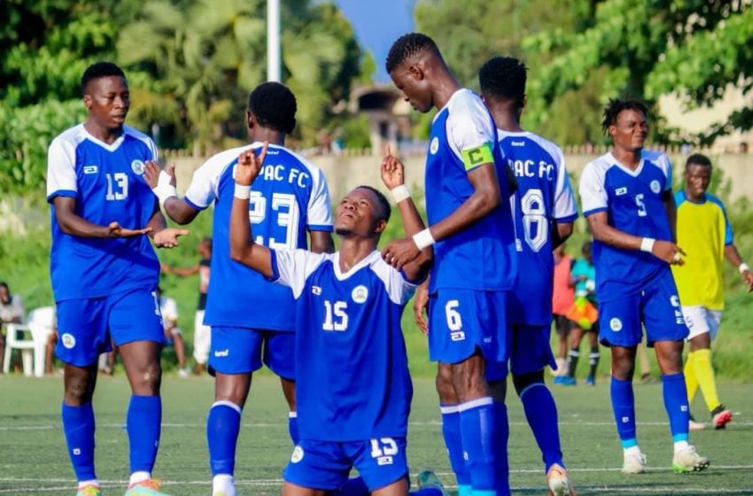 Joueurs en maillots bleus célébrant un but sur un terrain de football verdoyant avec des arbres en arrière-plan