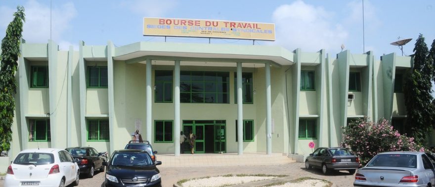 Façade d un bâtiment administratif avec plusieurs voitures garées devant et un panneau indiquant Bourse du Travail