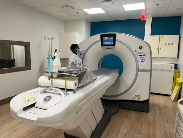 Scanner médical installé dans une salle avec un professionnel de santé portant un masque à proximité