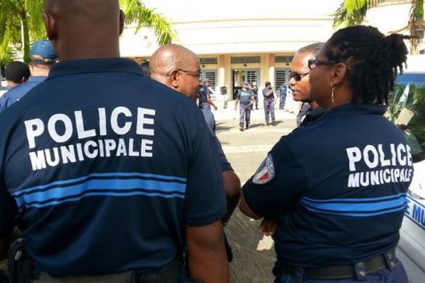 Policiers municipaux en uniforme discutant en plein air devant un bâtiment administratif.