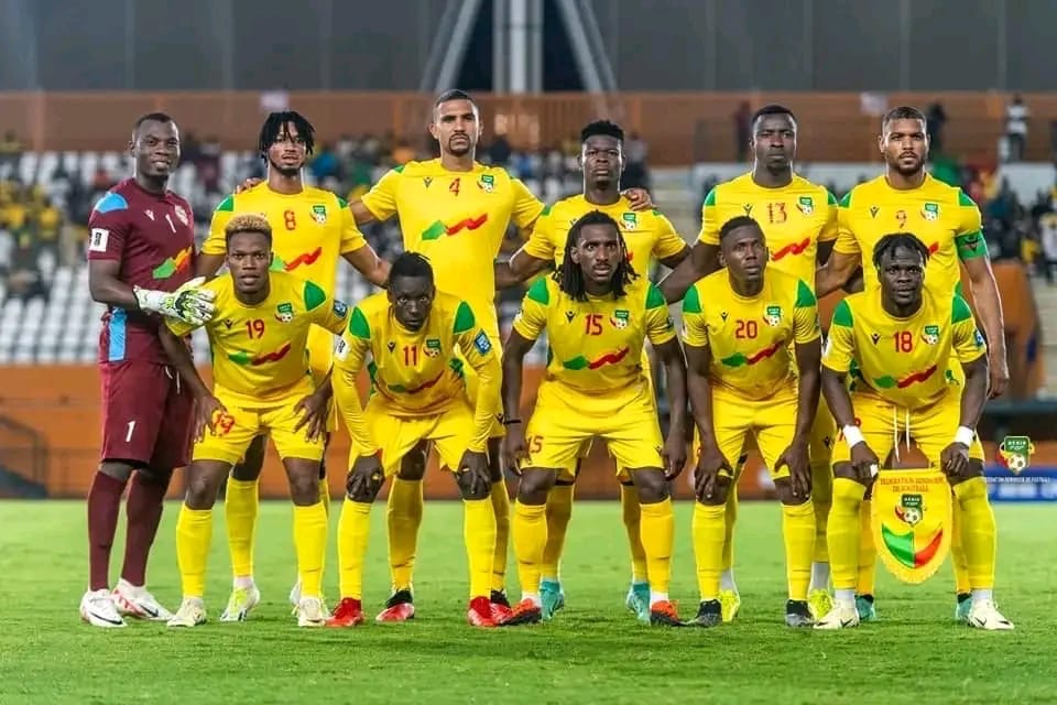 Équipe de football posant sur le terrain avant un match avec un joueur tenant un fanion bordé jaune et vert
