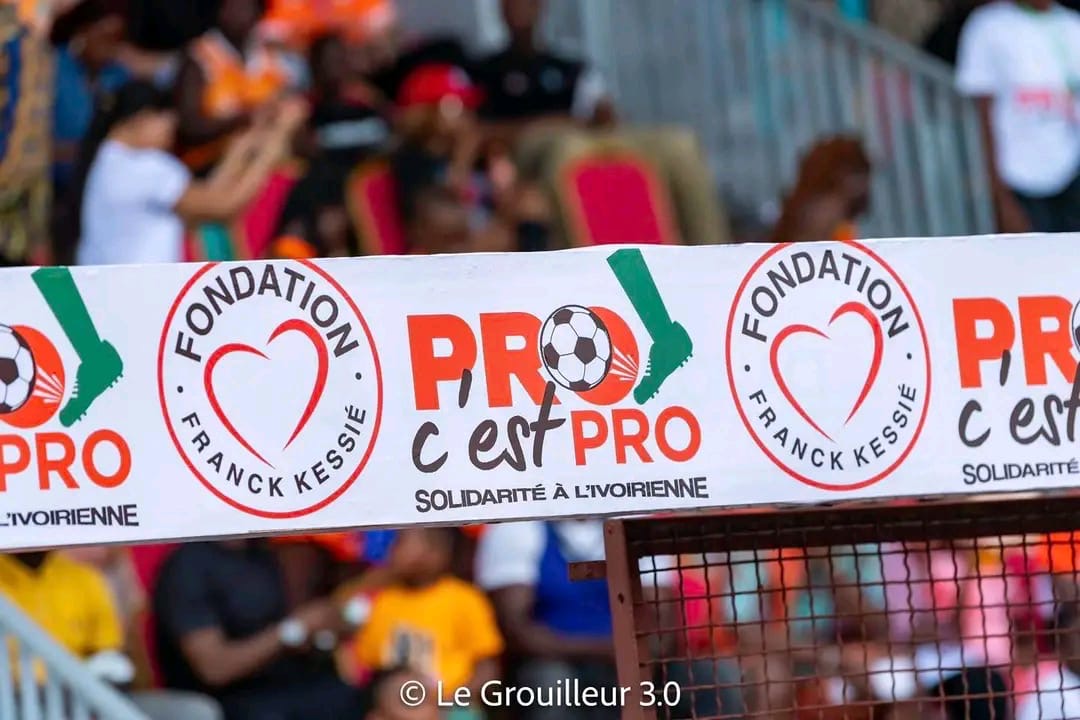 Bandes publicitaires avec logos et slogans d une fondation autour d un terrain sportif avec plusieurs spectateurs en arrière-plan