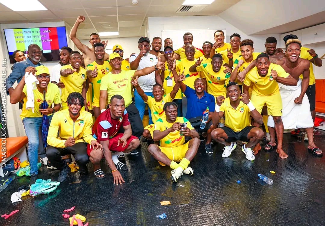 Groupe d hommes en tenue sportive jaune célébrant et posant avec gestes de victoire dans un vestiaire lumineux