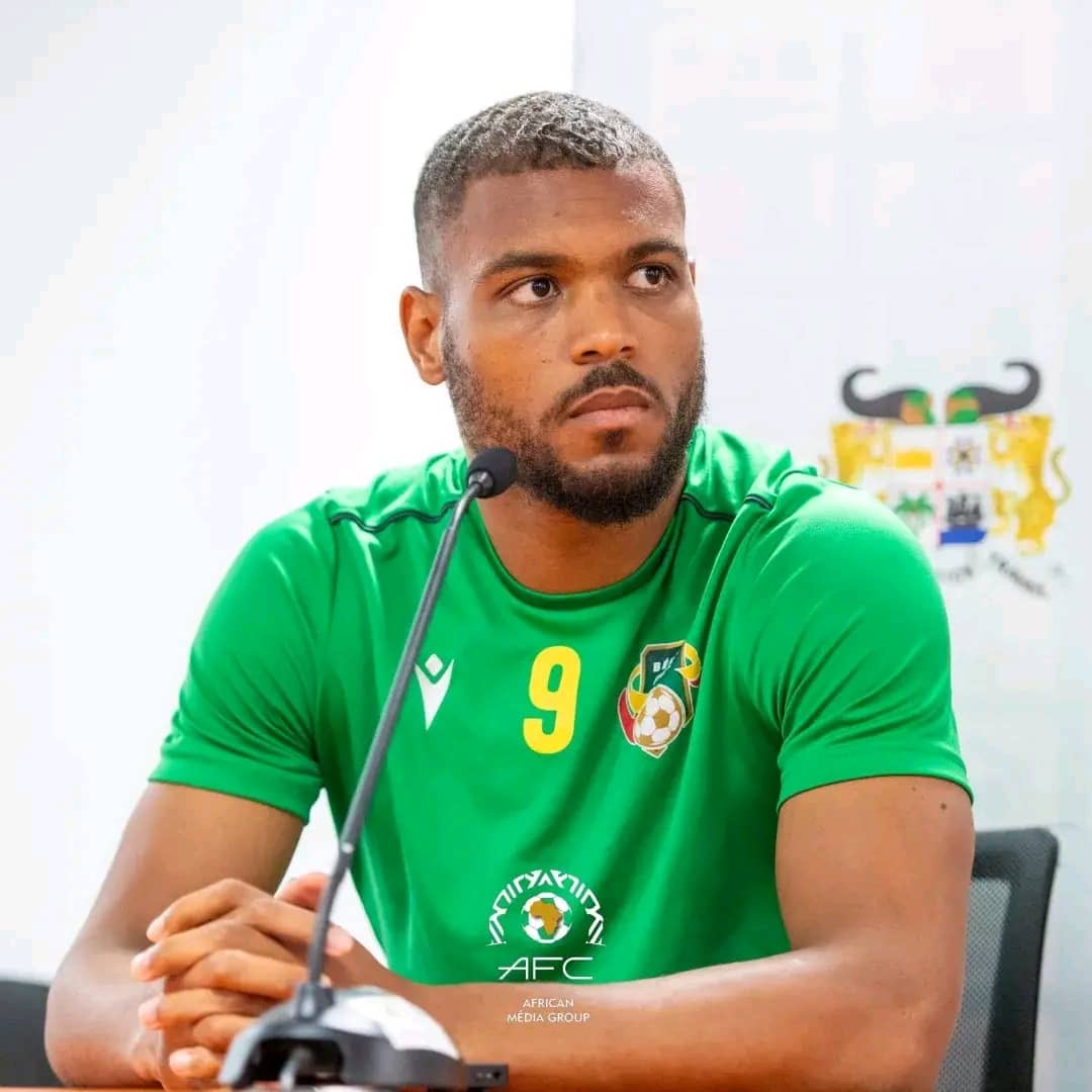 Homme en maillot vert numéro 9 assis devant un micro lors d'une conférence de presse