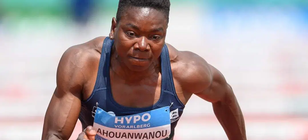 Athlète en tenue de course, concentrée et en pleine action sur une piste d'athlétisme lors d'une compétition