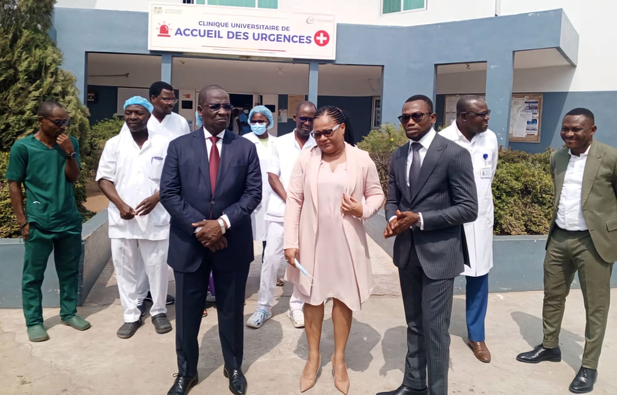 Un groupe de personnes habillées en tenue professionnelle devant l'entrée d'une clinique d'accueil des urgences