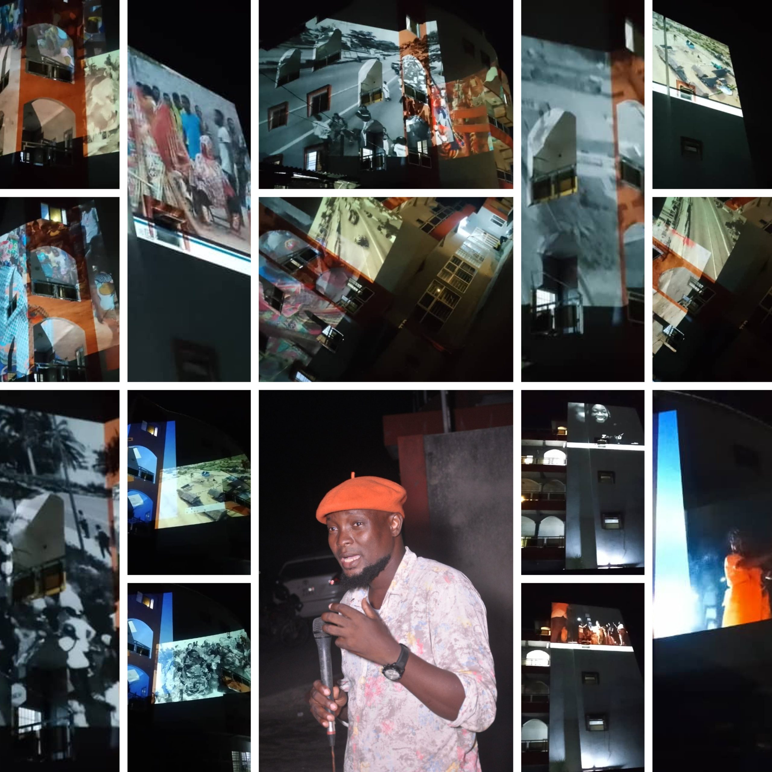 Un homme avec un béret orange parle au micro devant des projections vidéo colorées sur des murs la nuit