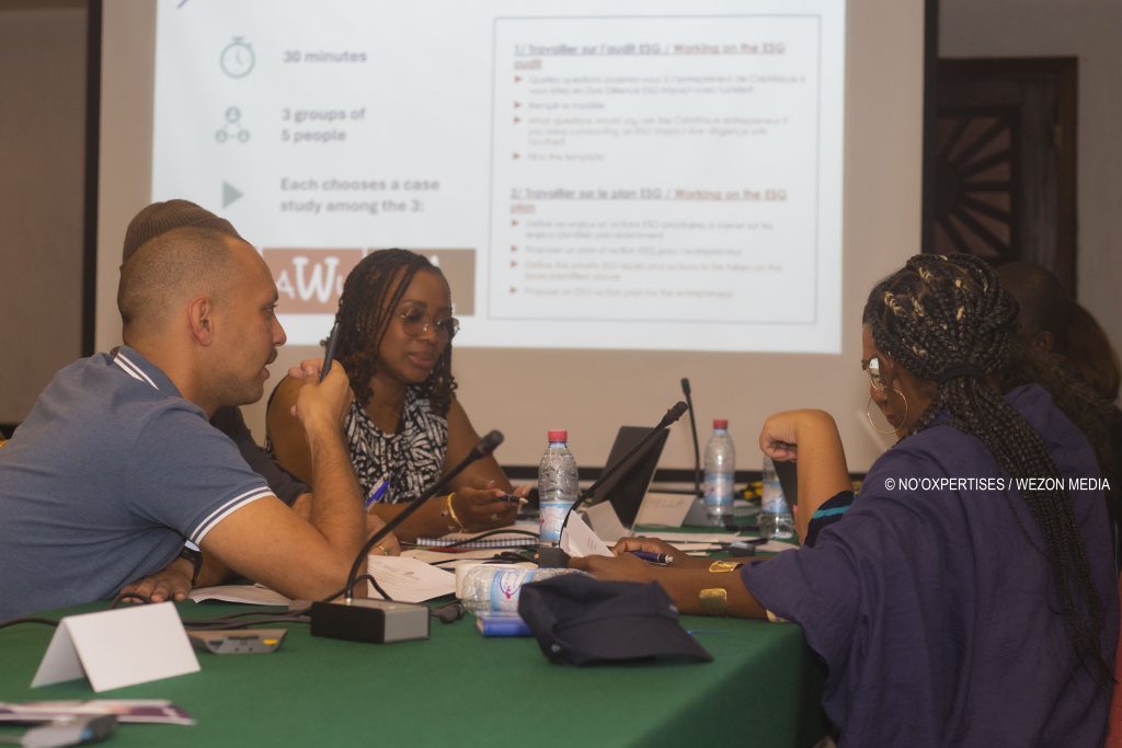 Quatre personnes discutent autour d’une table avec un écran projetant un document en arrière-plan