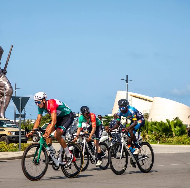 Quatre cyclistes en tenue colorée en pleine course sur une route urbaine par temps clair