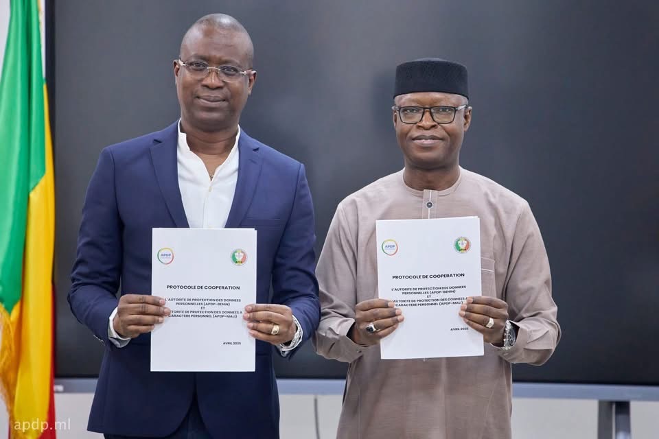 Deux hommes tenant un document officiel avec les drapeaux du Bénin en arrière-plan